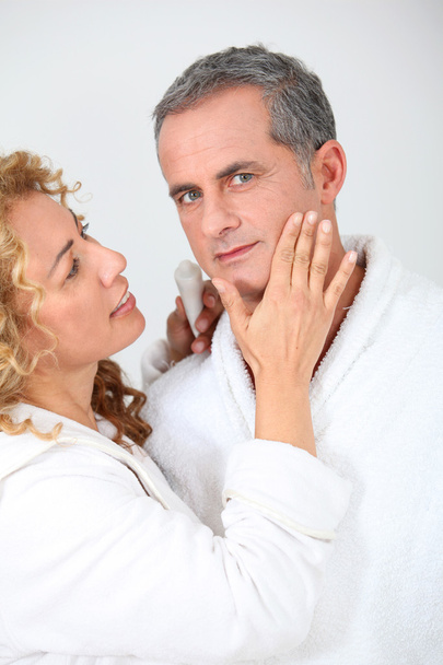 Kadın erkek arkadaşının yanağından nemlendirici uygulayarak - Fotoğraf, Görsel
