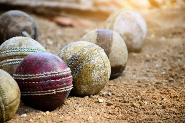 Старые мячи для тренировок и тренировок на песчаном полу рядом с кортом, мягкий и избирательный акцент на желтый мяч для крикета в середине. - Фото, изображение