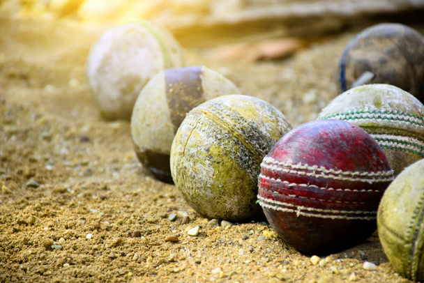 Alte Cricketbälle zum Training und Üben auf Sandboden neben dem Platz, weicher und selektiver Fokus auf gelben Cricketball in der Mitte. - Foto, Bild