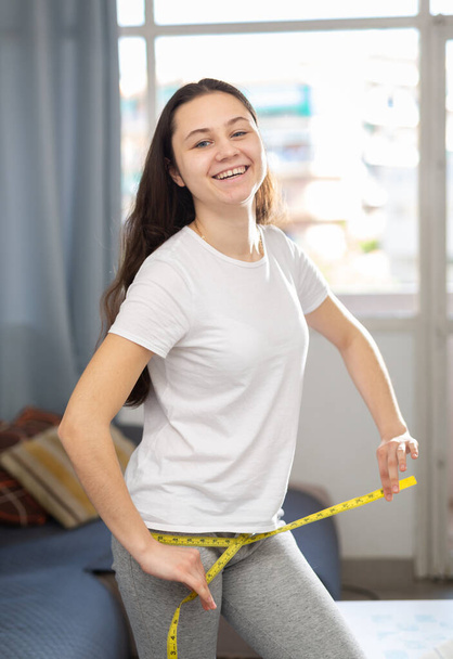 Positive woman measuring thigh with measuring tape - Photo, Image