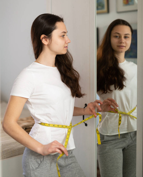 Portrait of woman taking measurements of waist - Photo, Image