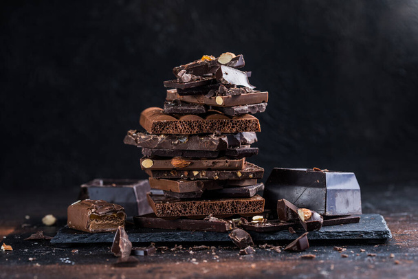 Çikolata kulesi parçaları. Fındık ve badem. Kırık çikolata parçaları. Tatlı yemek fotoğraf konsepti. - Fotoğraf, Görsel