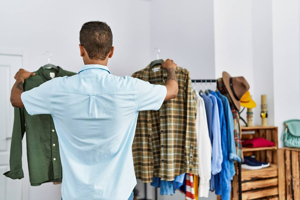 Young hispanic man buying choosing shirt at retail shop - Photo, Image