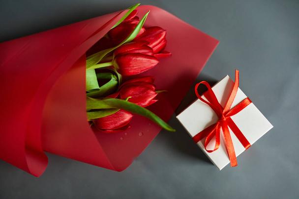 Vista dall'alto tulipani rossi fiori in carta rossa involucro con confezione regalo, sfondo festivo, concetto di Felice Festa della Mamma, Festa della Donna, compleanno, 8 marzo, San Valentino - Foto, immagini