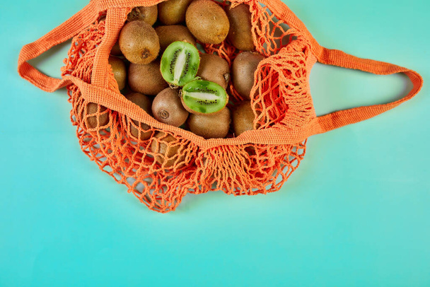 Flat lay Mesh grocery  shopping eco friendly bag with kiwi on blue canvas background, Zero waste cconcept, Local farmers market, shopping mall, top view, copy space, Plastic free items. - 写真・画像
