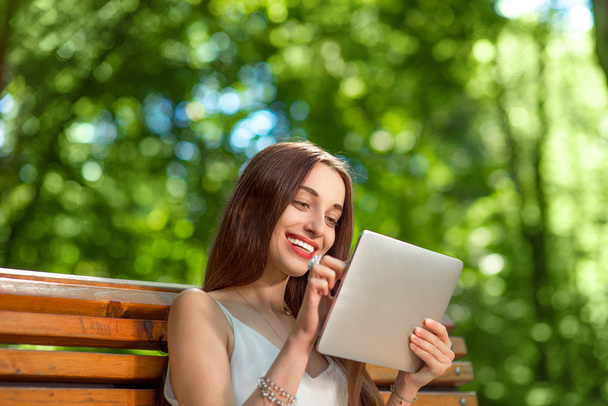 Jeune femme avec tablette numérique dans le parc
 - Photo, image
