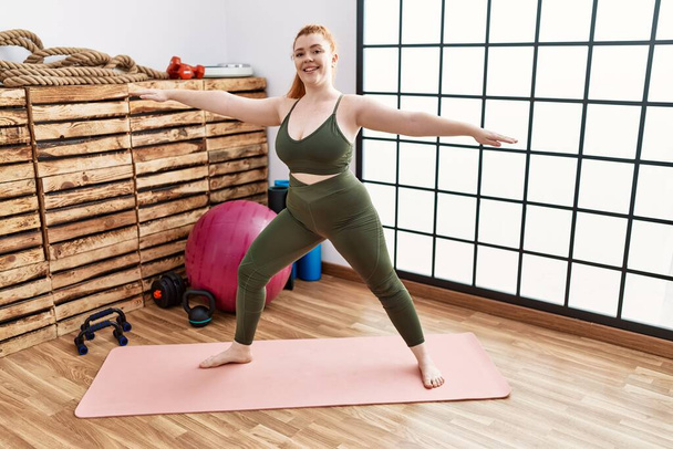 Mladá zrzka žena s úsměvem sebevědomý trénink jóga ve sportovním centru - Fotografie, Obrázek