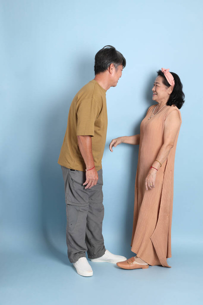 The cute senior Asian couple with casual clothes standing on the blue background. - Zdjęcie, obraz