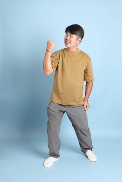 The senior Asian man with casual clothes standing on the blue background. - Foto, immagini
