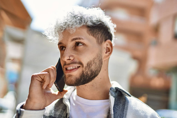 Jeune homme hispanique souriant smartphone parlant heureux à la ville. - Photo, image