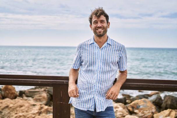 Young hispanic man smiling happy standing at the beach. - Valokuva, kuva