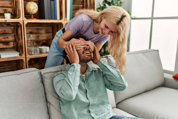Femme surprenant son petit ami avec les mains sur les yeux à la maison. - Photo, image