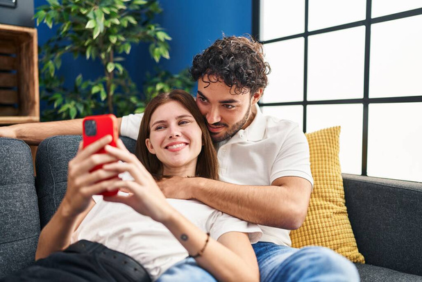 Mann und Frau umarmen sich zu Hause per Smartphone - Foto, Bild