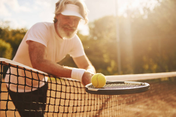Senior modern stylish man with racket outdoors on tennis court at daytime. - Foto, Imagen