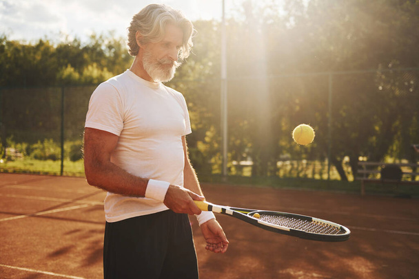 Training time. Senior modern stylish man with racket outdoors on tennis court at daytime. - Foto, Imagem