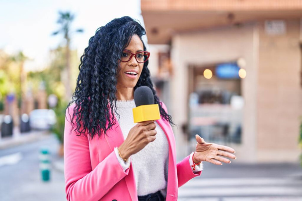 African american woman reporter working using microphone at street - Foto, Imagen