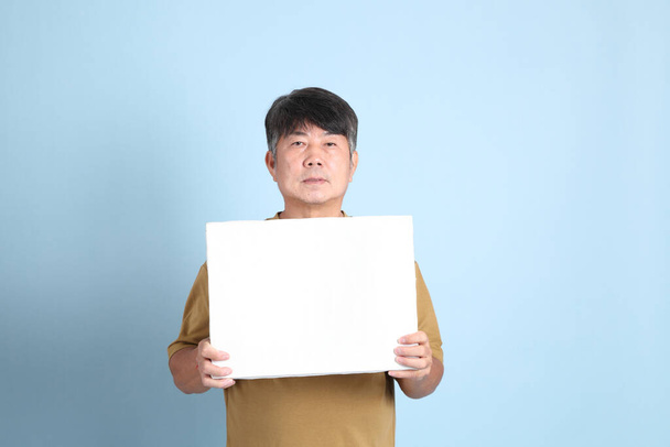 The senior Asian man with casual clothes standing on the blue background. - Fotoğraf, Görsel