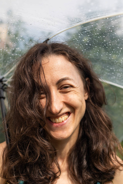 Portré egy mosolygós lányról esernyővel, egy nőről egy nyári esőben. - Fotó, kép