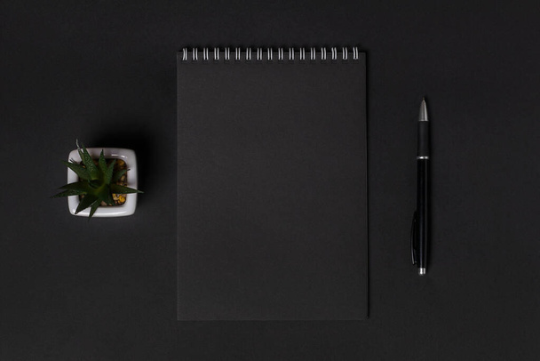 Prázdný zápisník s prázdnými černými listy na tmavém pozadí, kopírovací prostor, horní pohled. Obchodní nebo vzdělávací koncept. - Fotografie, Obrázek