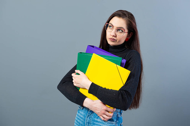 fashionable woman holding a colorfuls folders with documents, isolated on dark background - Foto, Bild
