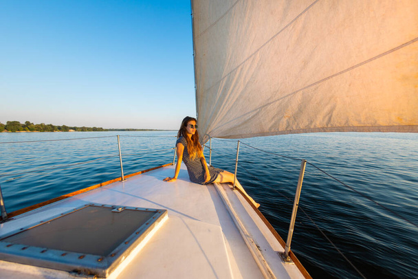 reizen op een jacht. een jong meisje zit op het achterschip van een wit jacht. privacy tijdens het reizen. - Foto, afbeelding