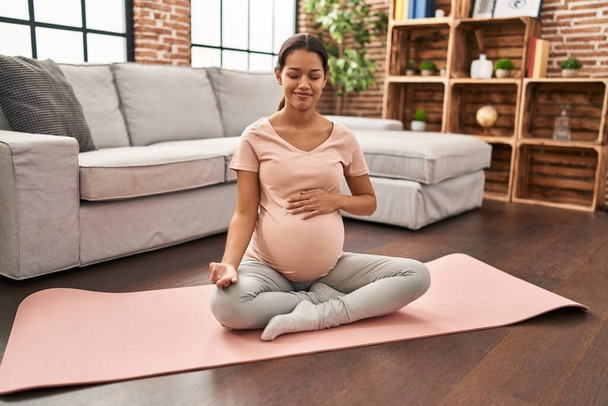 Young latin woman pregnant smiling confident training yoga at home - Photo, Image
