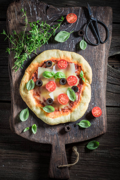 Homemade pizza made of tomatoes, cheese and olives. Pizza made of healthy vegetables and herbs. - Foto, Bild