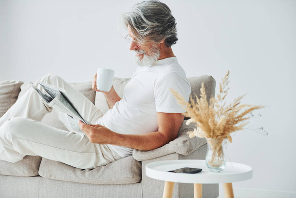 Having free time. Senior stylish modern man with grey hair and beard indoors. - Фото, изображение