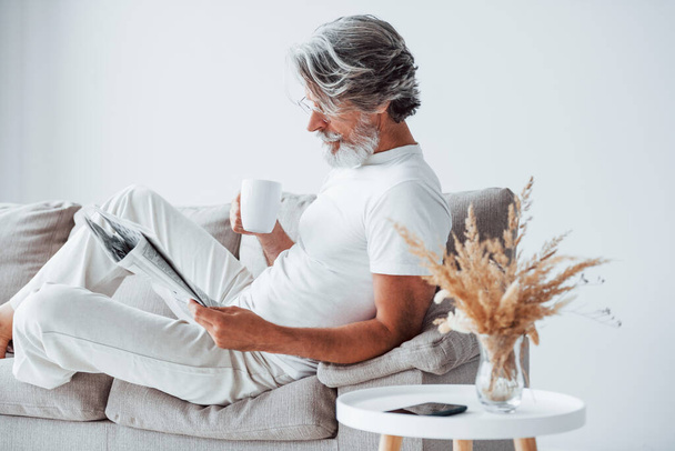 Having free time. Senior stylish modern man with grey hair and beard indoors. - Фото, изображение