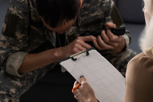 Емоційний військовий чоловік ділиться своїми думками з психотерапевтом, жестом, солдатом, який сидить на дивані перед психологом, внутрішньою клінікою. ПТСР і військова служба - Фото, зображення