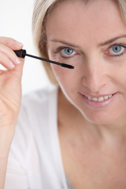 Beautiful blond woman applying makeup on her face - Φωτογραφία, εικόνα