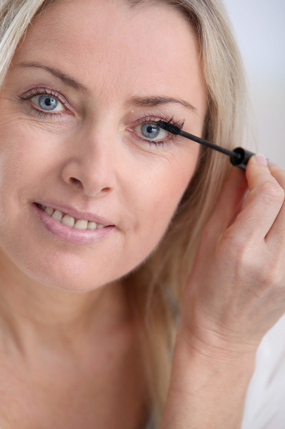 Beautiful blond woman applying makeup on her face - Zdjęcie, obraz