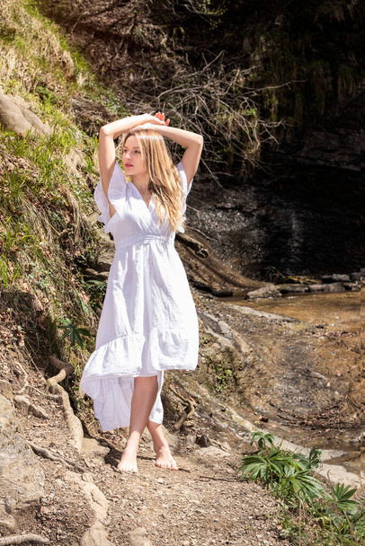 blondynka kobieta w białej sukience pozowanie w lesie w słoneczny dzień - Zdjęcie, obraz