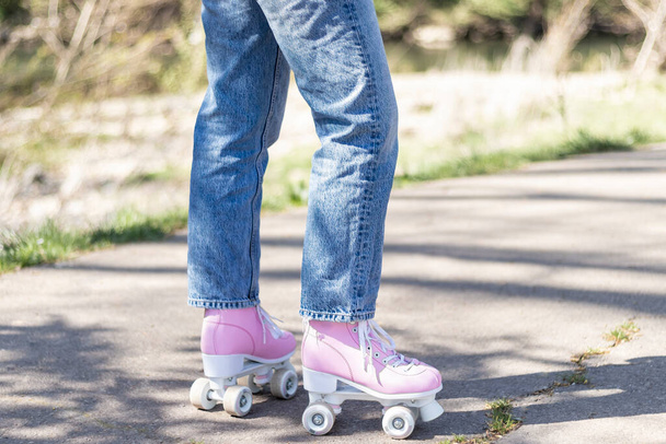 woman's legs in jeans and pink roller skates in a park - Foto, Imagem
