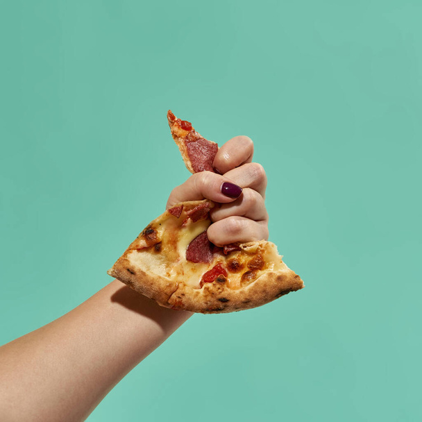Female hand squeezing slice of pepperoni pizza - Zdjęcie, obraz