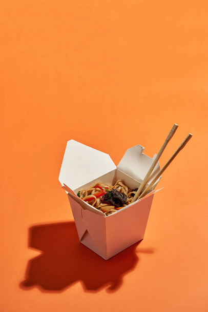 Asian noodles in takeaway box on orange background - Fotografie, Obrázek