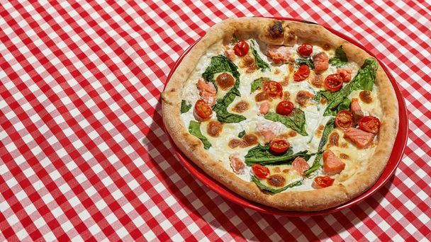 Pizza on plate on tablecloth over table in cafe - 写真・画像