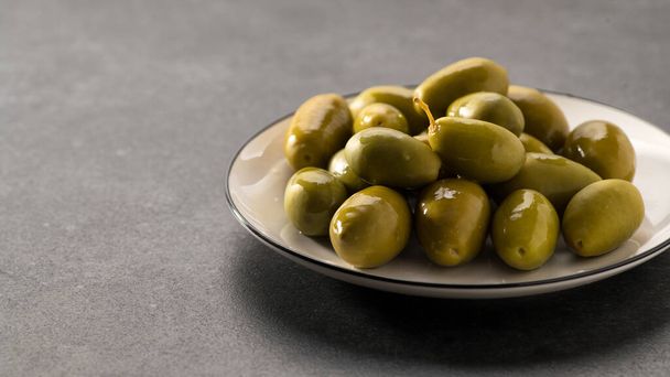Large green pickled olives on a dark gray background, close-up - Valokuva, kuva