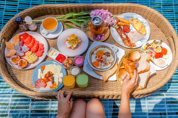 Bunte Mahlzeiten zum Frühstück oder Mittagessen mit Frauenhänden auf schwimmendem Tablett im Pool - Foto, Bild