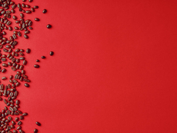 Geroosterde koffiebonen op rode achtergrond, met kopieerruimte. - Foto, afbeelding