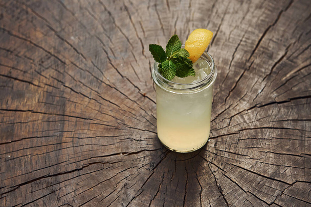 With lemon and mint. Close up view of fresh summer alcoholic cocktail on the wooden table. - Foto, Imagen