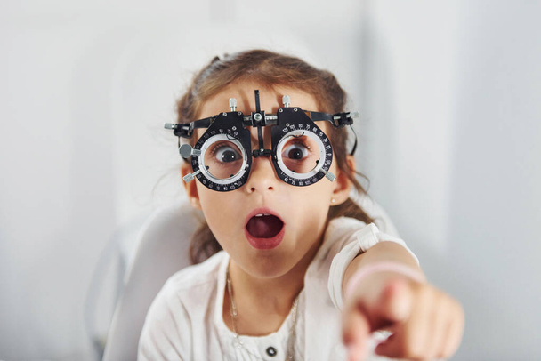 Cute little girl is in ophthalmology clinic with special tool on eyes getting tested. - Φωτογραφία, εικόνα