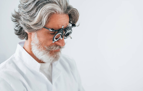 Senior man with grey hair and beard is in ophthalmology clinic. - Photo, image