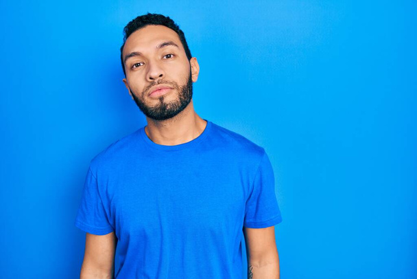Hispanic man with beard wearing casual blue t shirt relaxed with serious expression on face. simple and natural looking at the camera.  - Foto, Bild