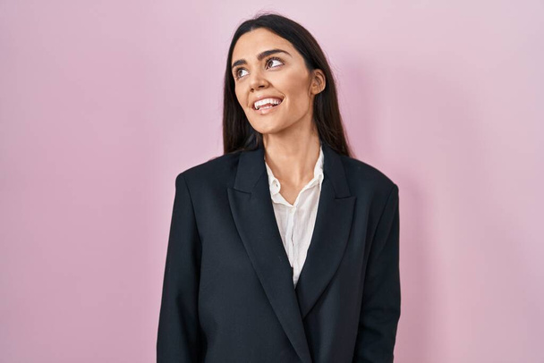Young brunette woman wearing business style over pink background looking away to side with smile on face, natural expression. laughing confident.  - Photo, Image