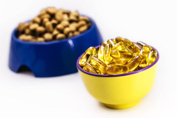 miska omega 3 pilulky s krmivem pro psy nebo kočky v pozadí, Vitamin doplněk Zabraňuje a kontroluje alergie a zánět, rozjasňuje srst, kopírovací prostor - Fotografie, Obrázek