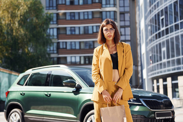 Młoda modna kobieta w burgundowym kolorze płaszcza w ciągu dnia z jej samochodu. - Zdjęcie, obraz