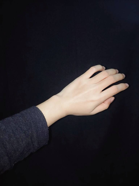 woman hand with black manicure on dark background - Fotoğraf, Görsel