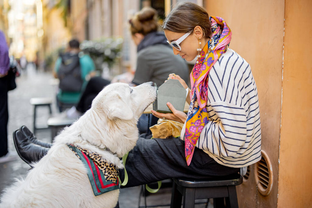 Mujer cuida a su perro mientras come pasta en la cafetería al aire libre - Foto, Imagen