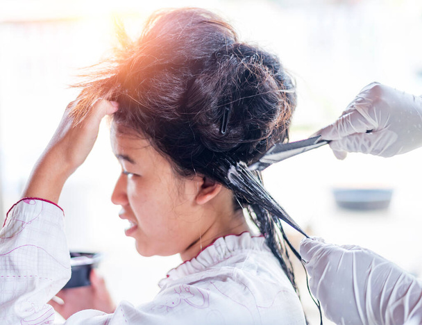 Fryzjer nakłada maskę na kobietę w salonie piękności. Procedura prostowania włosów botoksu i keratyny. - Zdjęcie, obraz